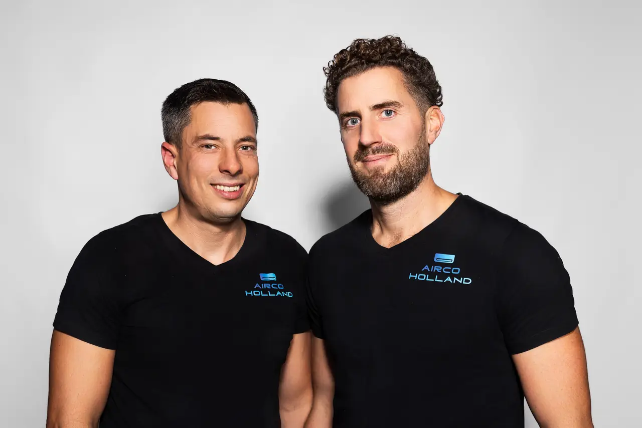 Peter (links) en Rein (rechts) van Airco Holland, lachend in zwarte shirts met het logo.