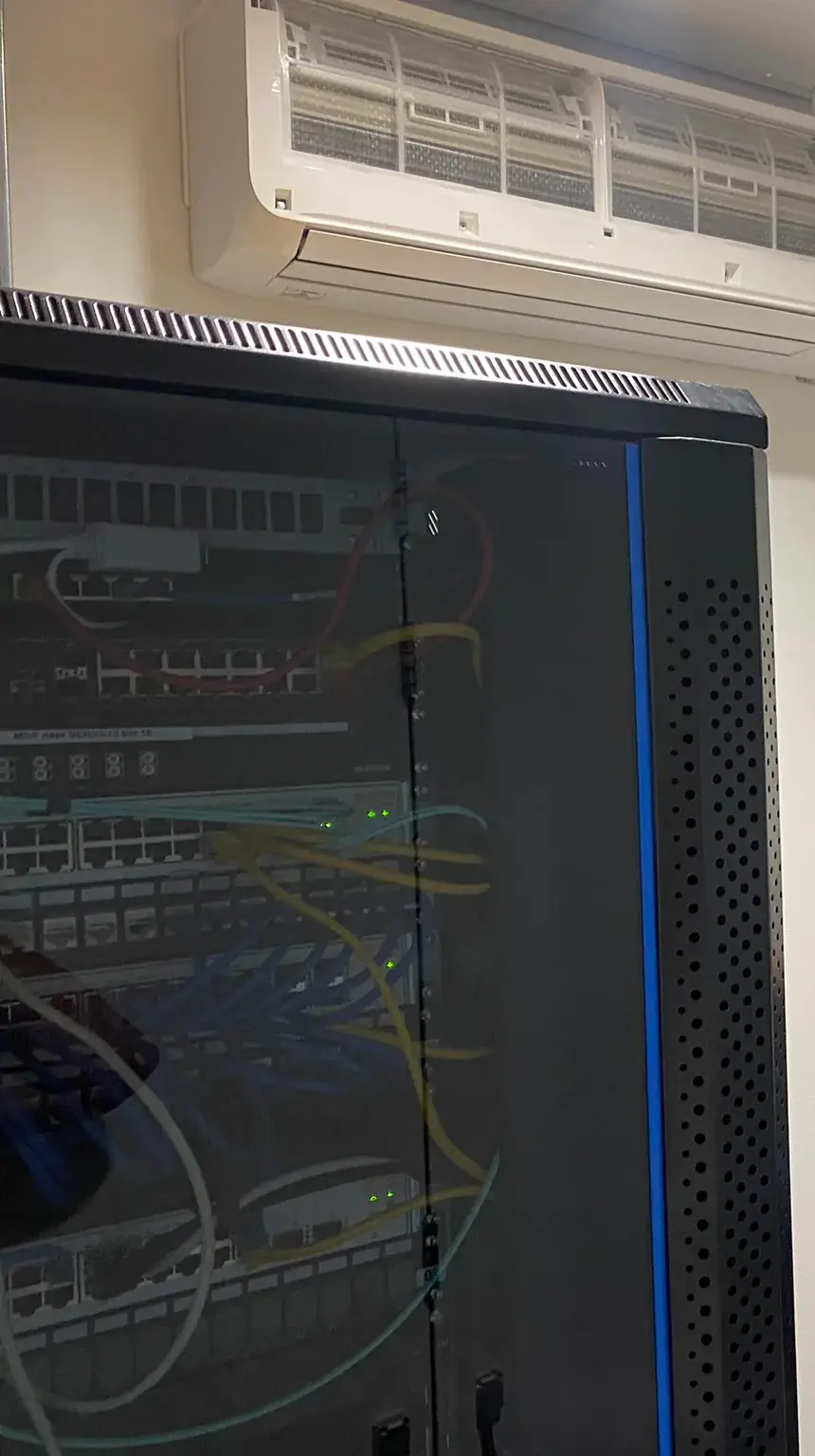 Een wandmodel hangt boven een zwart serverrek in een serverruimte.